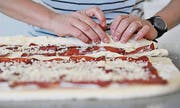 Die beliebig belegten Teigstücke werden auf der Längsseite eingerollt.