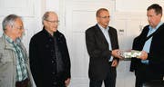 Mit strengem Blick überreicht IG-Hafen-Präsident Martin Dempfle (r.) mit den beiden IG-Mitgliedern Gion Camenisch (l.) und Heiner Löffler Gemeindeammann Norbert Senn die 822 Unterschriften als Geschenk verpackt. (Bild: Manuel Nagel)
