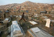 Afghanische Alltagsszene: Ein Bub spielt mit einem Reifen auf einem Friedhof in einem Kabuler Aussenquartier. (Bild: Rahmat Gul/AP)