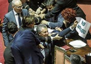 Gerangel im italienischen Senat, als ein Gegner des umstrittenen Gesetzes ein Plakat mit der Aufschrift «Stopp Invasion» in die Höhe hält. (Bild: Giuseppe Lami (15. Juni 2017, Rom))