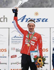 Daniel Hubmann stemmt in Arosa nach seinem grossen Triumph den Pokal in die Höhe. (Bild: ky/Gian Ehrenzeller)