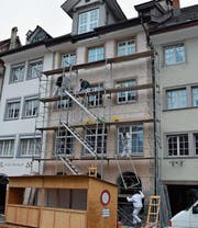 Die Maler bauen das Baugerüst wieder ab. Die untere Hälfte befindet sich noch im ursprünglichen Zustand. Oben wurde die Fassade für den neuen Anstrich vorbereitet. (Bild: Gianni Amstutz (11. Dezember 2017))