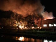 Flammen und dicker, stinkender Rauch dringen aus der brennende Gewerbehalle. (Bild: Polizei Basel-Landschaft)