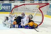 Kloten Flyers Stürmer Peter Müller wird von Santeri Alatalo bearbeitet, hinten Torhüter Eero Kilpelainen. (Bild: Keystone)