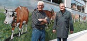 Tier- und Pferdemaler Heinz J. Berchtold sowie Viehhändler und Metzger Otto Baumgartner stehen vor der bemalten Stallfassade. (Bild: Yvonne Aldrovandi-Schläpfer)