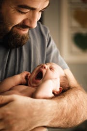 Ein Vater hält sein Bébé im Arm. (Bild: Getty)