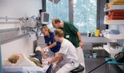 Robert Sieber (im grünen Kittel), Leiter der Notfallaufnahme des Kantonsspitals, untersucht mit Kollegen die Beinwunde einer Patientin. (Bilder: Ralph Ribi)