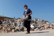 Zwei Personen betrachten ein eingestürztes Gebäude in Cavezzo. (Bild: Keystone / EPA)