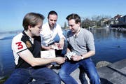 Die drei Unternehmer Marc Dür, Samuel Lutherbacher und Elio Reinschmidt mit ihrem Kartenspiel am Zugersee. Bild: Werner Schelbert (19. April 2018)