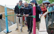 Felix Buschor und Werner Ackermann (von links) durchschneiden das grüne Band zur Eröffnung des Baumwipfelpfades. (Bild: Martin Knoepfel)