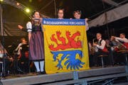 Die Ehrendamen Fabienne Häne, Lorena Segmüller und Martina Häne (von links) enthüllen die neue Vereinsfahne der Blechharmonie Kirchberg.Bilder: Beat Lanzendorfer (Bild: Beat Lanzendorfer)