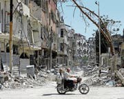 Zwei Syrer fahren mit dem Motorrad durch die zerstörte Stadt Duma. (Bild: Louai Beshara/AFP (16. April 2018))