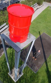 Signerbrunnen in St.Gallen. Der starke, satte Wasserstrahl aus dem roten Fass klatscht auf den schwarzen Asphalt, und zerstiebt in tausend Tropfen.