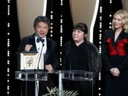 Regisseur Hirokazu Kore-Eda nimmt in Cannes die Goldene Palme für sein berührendes Familiendrama "Shoplifters" entgegen. (Bild: KEYSTONE/EPA/SEBASTIEN NOGIER)