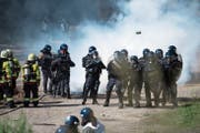 Einsatzkräfte der Polizeikorps von Luzern, Nid- und Obwalden schützen sich bei der Übung vor Tränengas (oben). Danach bringen sie Feuerwehrleute in Sicherheit. (Bild: Corinne Glanzmann; Schüpfheim, 25. Mai 2018)