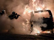 Feuerwehrleute löschen bei den Krawallen rund um den G20-Gipfel von 2017 in Hamburg ein brennendes Auto. Elf Monate später sind in mehreren Ländern Verdächtige befragt worden, auch in der Schweiz. (Bild: KEYSTONE/EPA/CLEMENS BILAN)