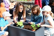 Lehrerin Fabienne Haller bepflanzt mit Schülern einen Trog. (Bild: Werner Lenzin)