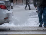 Ein Auto stösst Abgase neben einem Fussgänger aus (Bild: KEYSTONE/MELANIE DUCHENE)