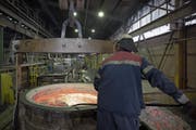 Ein Mitarbeiter der Trimet Aluminium SE entfernt Schmutz aus geschmolzenem Aluminium. (Bild: Jasper Juinen/Bloomberg (Essen, 4. Mai 2018))
