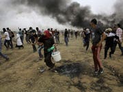 Palästinensische Demonstranten im Gazastreifen versuchen sich vor Tränengas der israelischen Armee zu retten. (Bild: KEYSTONE/AP/ADEL HANA)