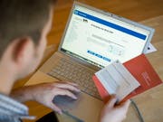 Ein Mann studiert am Laptop die Unterlagen für eine Abstimmung per e-Voting (Bild: KEYSTONE/ALESSANDRO DELLA BELLA)