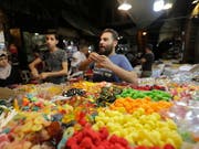 Die Menschen in Syrien decken sich auf einem Markt in Damaskus mit Süssigkeiten ein für Eid al-Fitr, das Fastenbrechen nach dem Ramadan. (Bild: KEYSTONE/EPA/YOUSSEF BADAWI)