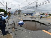 Arbeiter checken die Schäden durch ein Erdbeben an einer Strasse. (Bild: KEYSTONE/EPA-EFE/JIJI PRESS)