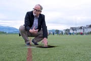Der Marketing-Chef des FC Hünenberg, Christoph Stuber, zeigt den maroden Kunstrasen, welcher saniert werden muss. (Bild: Maria Schmid, 16. Mai 2018)