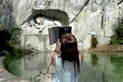 Eine Touristin fotografiert das Löwendenkmal in der Stadt Luzern. (Bild: Nadia Schärli)