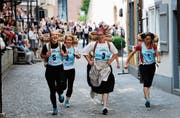 Oben: Eine sichtlich spassige Sache – mit den Hutten auf dem Rücken hetzen die Frauen durch die Altstadt. Unten links: Auch der Nachwuchs rennt mit und bugsiert die Leitern durch die Gassen. Unten rechts: Daniel Burch, Präsident Zuger Kantonsrat, gratuliert dem Team Costa Rica, Boris Alonso Sosa Centeno und Ricardo Cerdas Cortes. Die beiden Gäste aus der Ferne holten den vierten Platz. (Bild: Stefan Kaiser (Zug, 25. Juni 2018))