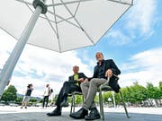 Endlich: Die Zürcher Stadträte Richard Wolff (links) und Filippo Leutenegger (rechts) können auf dem Sechseläutenplatz unter einem robusten Sonnenschirm den Schatten geniessen. Das Vorgängermodell war vom Winde verweht und zerzaust worden. (Bild: KEYSTONE/WALTER BIERI)
