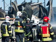 Feuerwehrleute überwachen am Donnerstag die Brandstätte auf dem Gelände der Sägerei Despond, die dem Freiburger SVP-Nationalrat Jean-François Rime gehört. (Bild: KEYSTONE/THOMAS DELLEY)