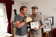 Hochgeschätzte Sportmemorabilien: Markus Brandes (links ) mit dem signierten Boxhandschuh von Muhammad Ali, sein Mitarbeiter Josip Konjevod zeigt das Karate-Instruktionsbuch von Bruce Lee.