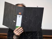 Der wegen Kindesmissbrauchs angeklagte Schweizer sitzt mit einen Aktenordner vor seinem Gesicht in einem Saal des Freiburger Landgerichts. (Bild: Keystone/DPA/PATRICK SEEGER)