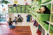 Eine Betreuerin der Kita Small Foot in Luzern hilft einem Kind in der Garderobe beim Anziehen. (Bild: Dominik Wunderli, 22. Mai 2018)