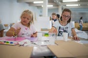 Die Kinder bemalen eine Kartonschachtel, als wäre es ein Raum in einem Haus.