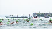 Von Booten begleitet, schwimmen die Teilnehmer der Seeüberquerung von Steckborn (im Hintergrund) nach Hemmenhofen auf der Halbinsel Höri (D). (Bild: PD/Chris Sigrist)