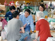 Japans Regierungschef Shinzo Abe (Mitte) spricht den Betroffenen der Unwetterkatastrophe Mut zu. (Bild: KEYSTONE/AP Kyodo News/SHOHEI MIYANO)