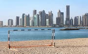 Ein Tor im Wüstensand vor der Skyline von Doha, der Hauptstadt des Emirats Qatar. (Bild: Keystone)