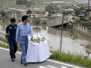 Ministerpräsident Shinzo Abe bei einem Besuch in den japanischen Überschwemmungsgebieten. (Bild: KEYSTONE/EPA JIJI PRESS)