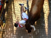Einer der gehetzten Bullen bei der Stierhatz im spanischen Pamplona schleift einen Läufer an dessen Halstuch mit sich. (Bild: KEYSTONE/EPA/RODRIGO JIMENEZ)