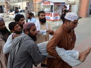 Helfer bringen ein verletztes Opfer des Anschlages in Pakistan in Sicherheit. (Bild: KEYSTONE/EPA/JAMAL TARAQAI)