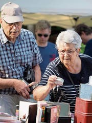 Kaufen oder nicht: Eine Flohmarkt-Besucherin sieht sich eine Büchse genauer an. (Bild: Andreas Taverner)