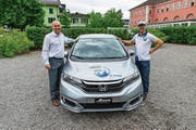 Reto Flury vom OK (mit Kappe) und Vital Hotz von der Auto Hotz AG präsentieren den Hauptpreis der Dorf-Fäscht-Tombola. (Bild: PD)