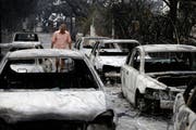 Ein Mann läuft in Mati, östlich von Athen, an ausgebrannten Autos vorbei. (Bild: AP Photo/Thanassis Stavrakis, 24. Juli 2018)