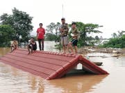 Nach dem Bruch eines Staudamms haben sich Dorfbewohner in Laos auf das Dach eines überfluteten Hauses gerettet. (Bild: KEYSTONE/EPA ABC LAOS NEWS)