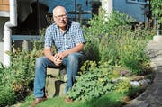 Hanspeter Horsch in seinem heimischen Garten. Neben ihm die Pflanze Frauenmantel, die vor allem bei Zyklusbeschwerden Abhilfe schafft. (Bild: Astrid Zysset)