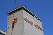 Von einem Hängekorb aus werden das Mühlrad-Symbol und der Schriftzug «eberle mühlen» in rund 50 Metern Höhe abmoniert. Der Pneukran befindet sich auf der anderen Seite der Mühle. Der Kranführer steht per Funk mit einem Helfer und dem Mann im Korb in Kontakt. (Bild: Hans Suter)