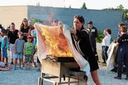 Unter Anleitung löscht eine Besucherin eine brennende Pfanne. (Bild: Barbara Hettich)