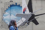 Eine Frau läuft am Wandbild zur Erinnerung an den Absturz des MH370-Fluges vorbei. (Bild: EPA/ Fazry Ismail, Kuala Lumpur, 29. Juli 2018)